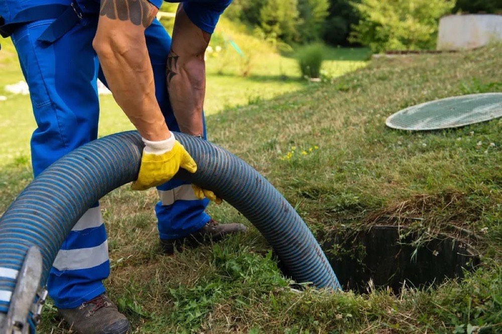 Kevin aan het werk met de hogedrukslang bij een inspectieput